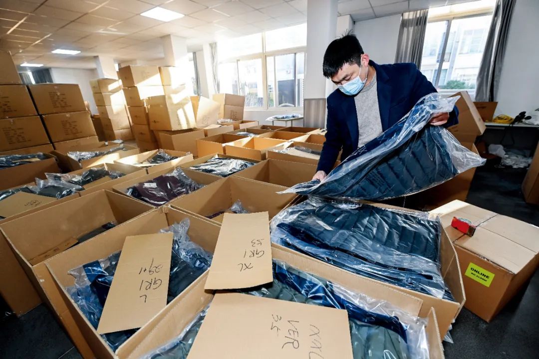 2022年12月14日，在位于浙江嘉兴市南湖创业园一家服饰公司的仓库内，工作人员在打包一批外贸服装。图/新华