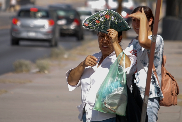 一名女子拿着扇子站在墨西哥华雷斯城街头。新华社资料