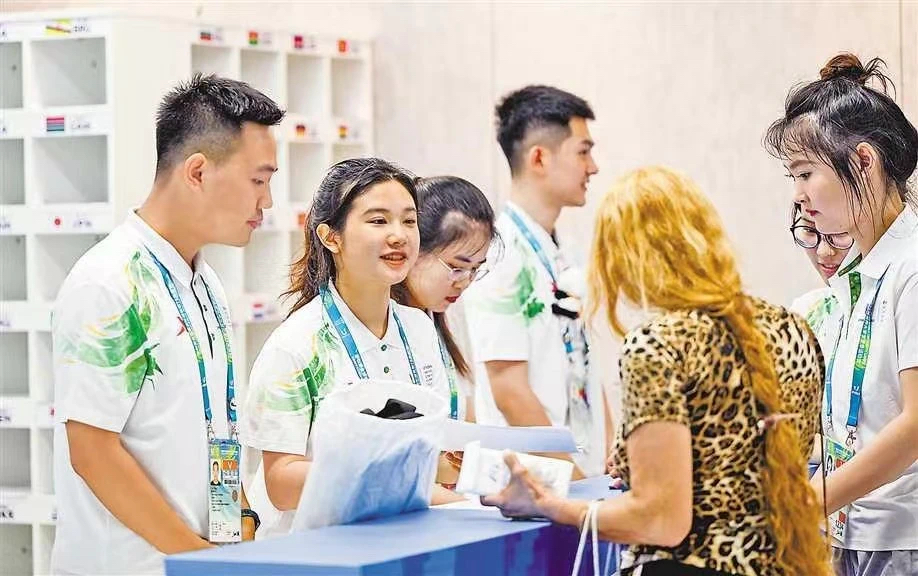 四川外国语大学志愿者在大运村代表团服务中心提供服务。图据重庆日报