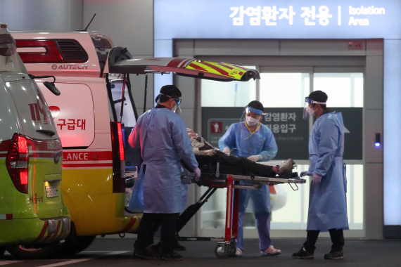 2022年3月22日，在韩国首尔，医务人员运送新冠患者至急救医疗中心。新华社资料